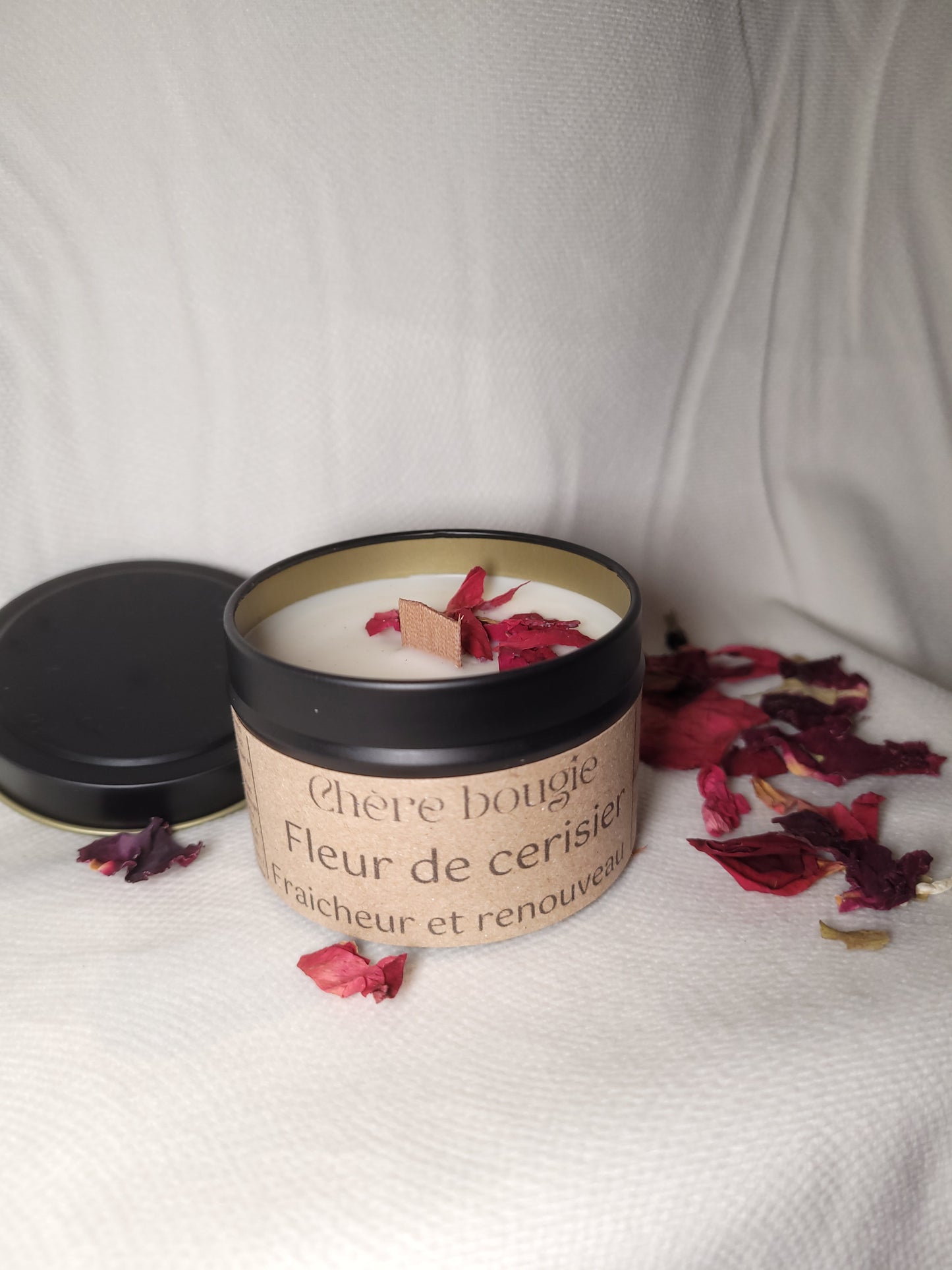 Bougie artisanale fleur de cerisier, présentée dans un élégant contenant en métal noir avec une lumière douce.