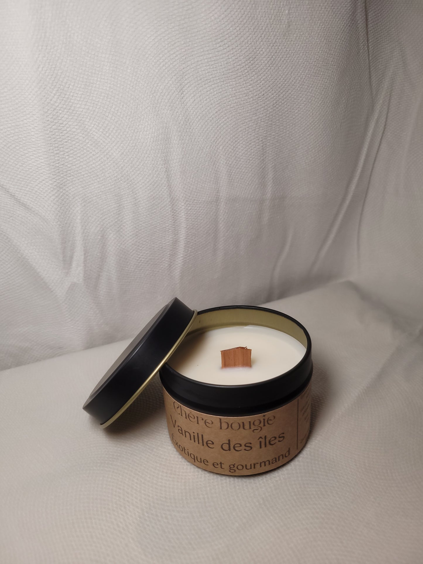 Bougie artisanale dans un élégant contenant en métal noir, parfumée à la vanille des îles, décorée sur un fond en bois.