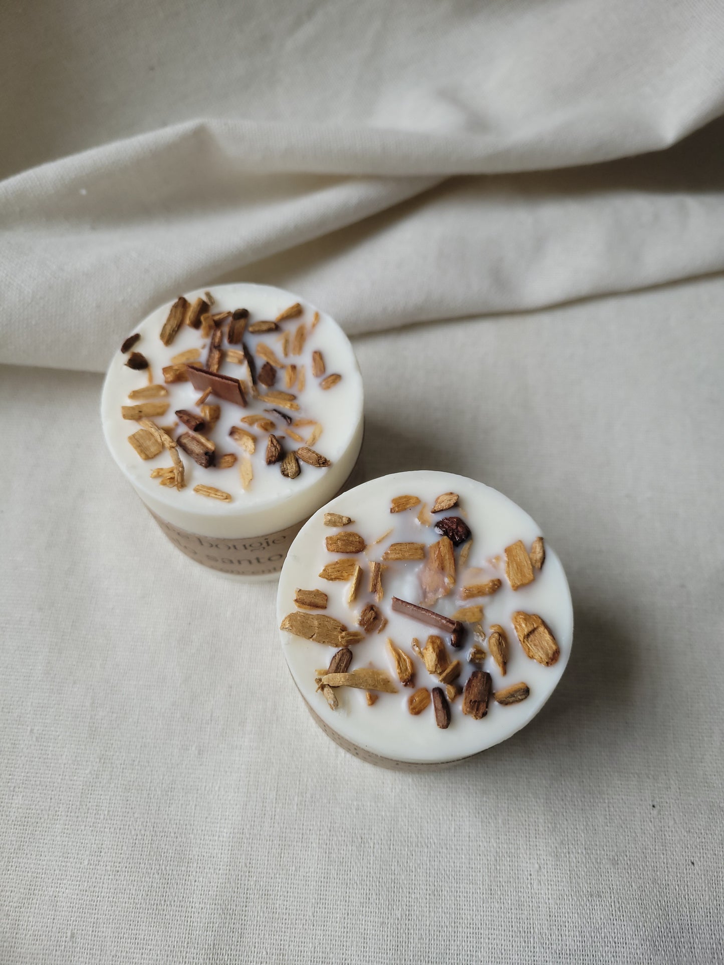 Bougie artisanale à la senteur Palo Santo placée sur une table, entourée d’éléments naturels pour une ambiance zen.