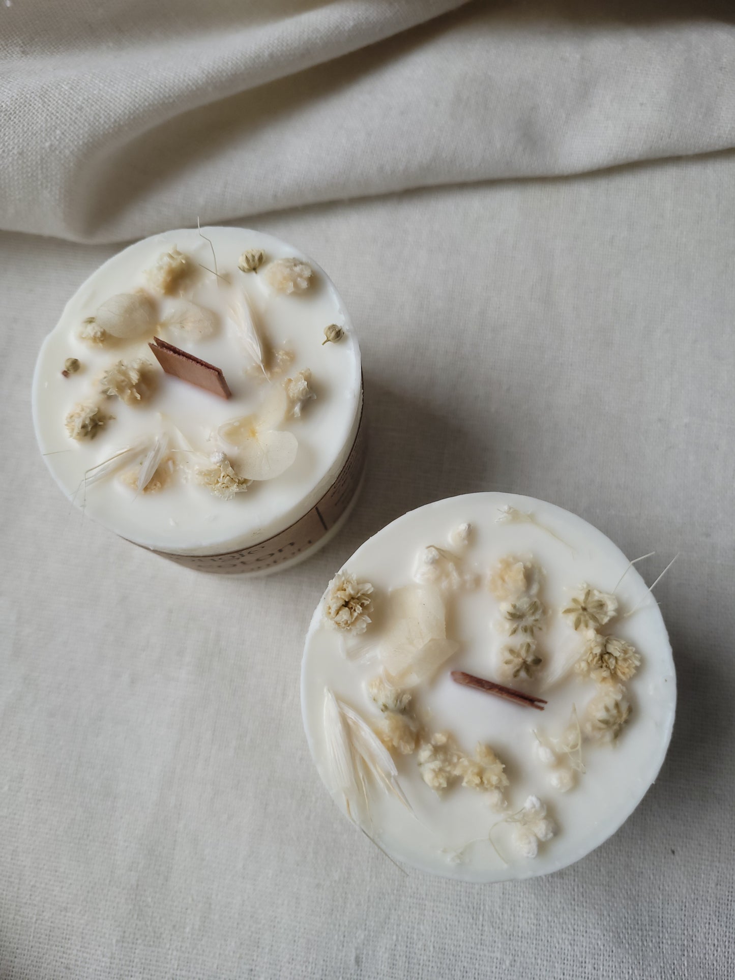 Bougie fleur de coton allumée, diffusant une ambiance douce et apaisante dans un intérieur cozy.