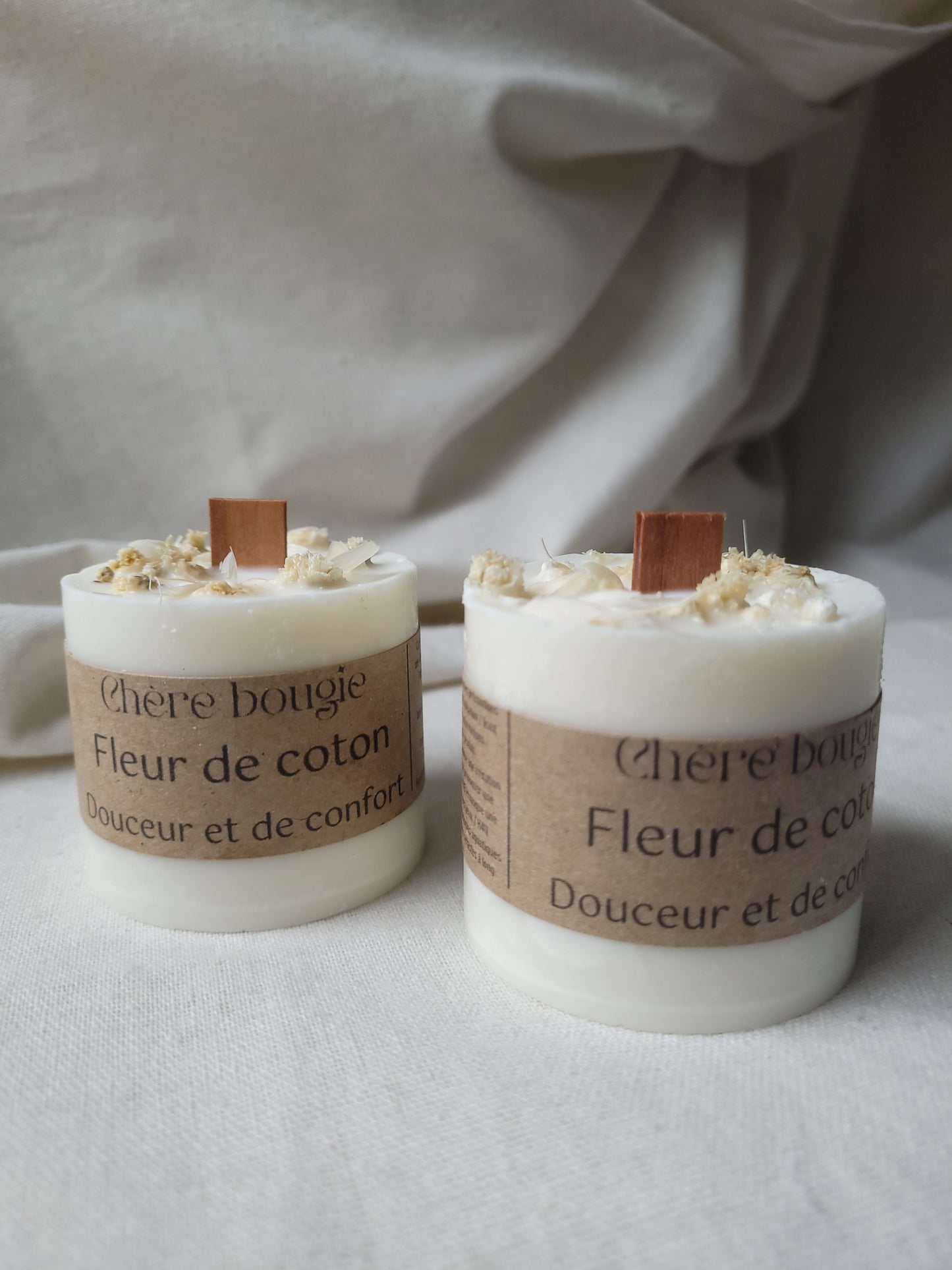 Éléments naturels entourant la bougie fleur de coton, illustrant son caractère artisanal et respectueux de l'environnement.