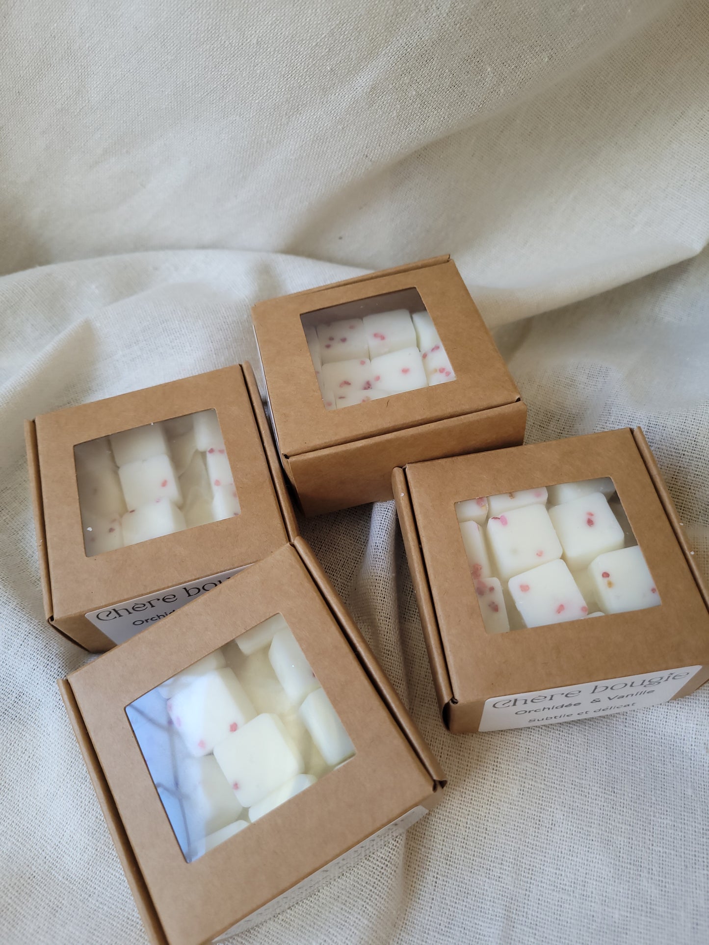 Boîte ouverte de fondants parfumés Orchidée Vanille, contenant 12 fondants brillants en cire de soja