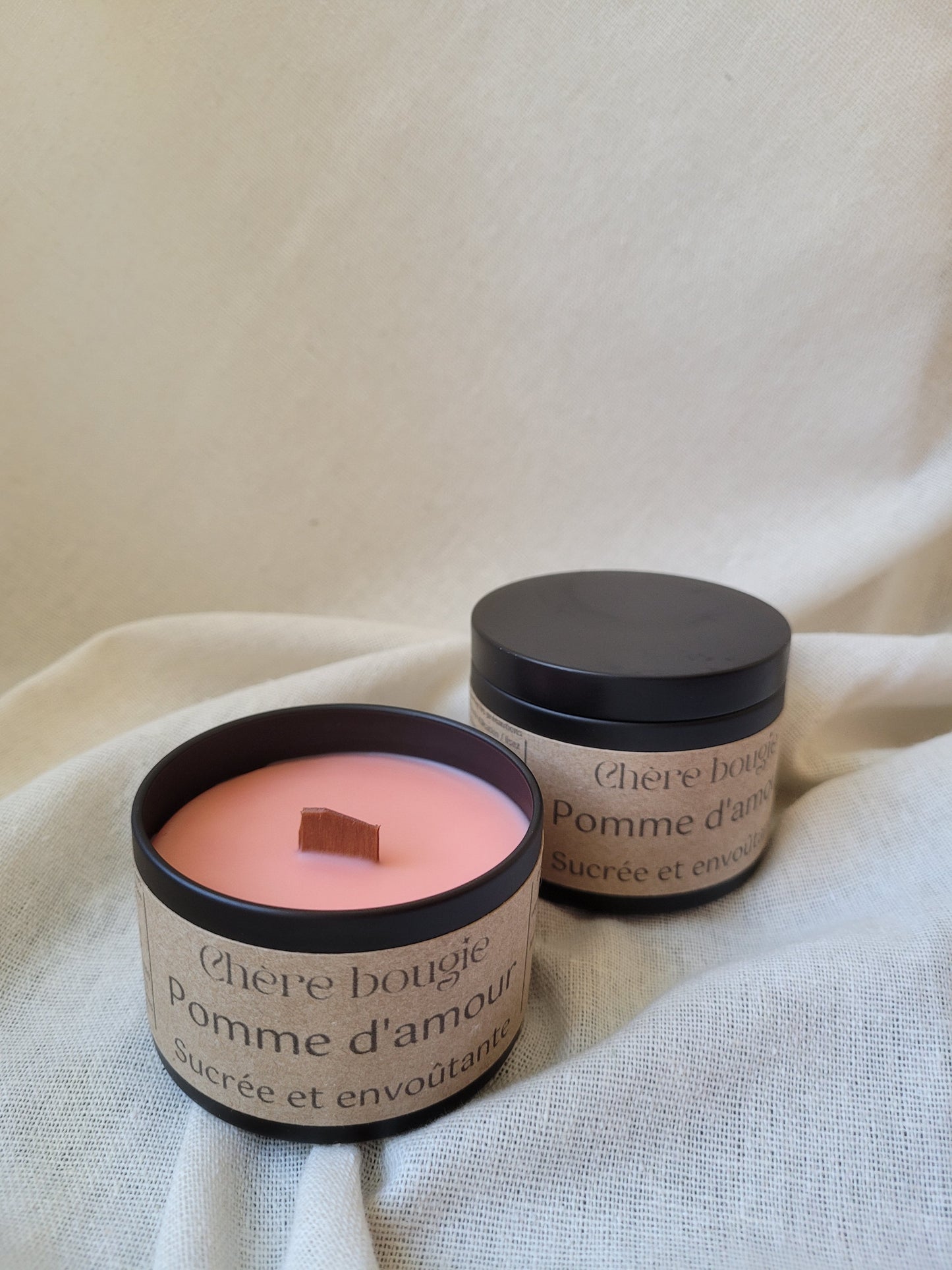 Bougie artisanale senteur pomme d’amour allumée dans un élégant contenant en métal noir, créant une ambiance douce et gourmande.